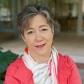 A woman with short grey hair and a pink jacket.